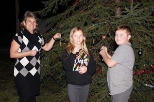 Melissa Elliott along with Kylie and Skylar Hickey, put some decorations on the tree donated by the Brown family out back of the Lions Hall in Verona last Friday night. Photo/Craig Bakay